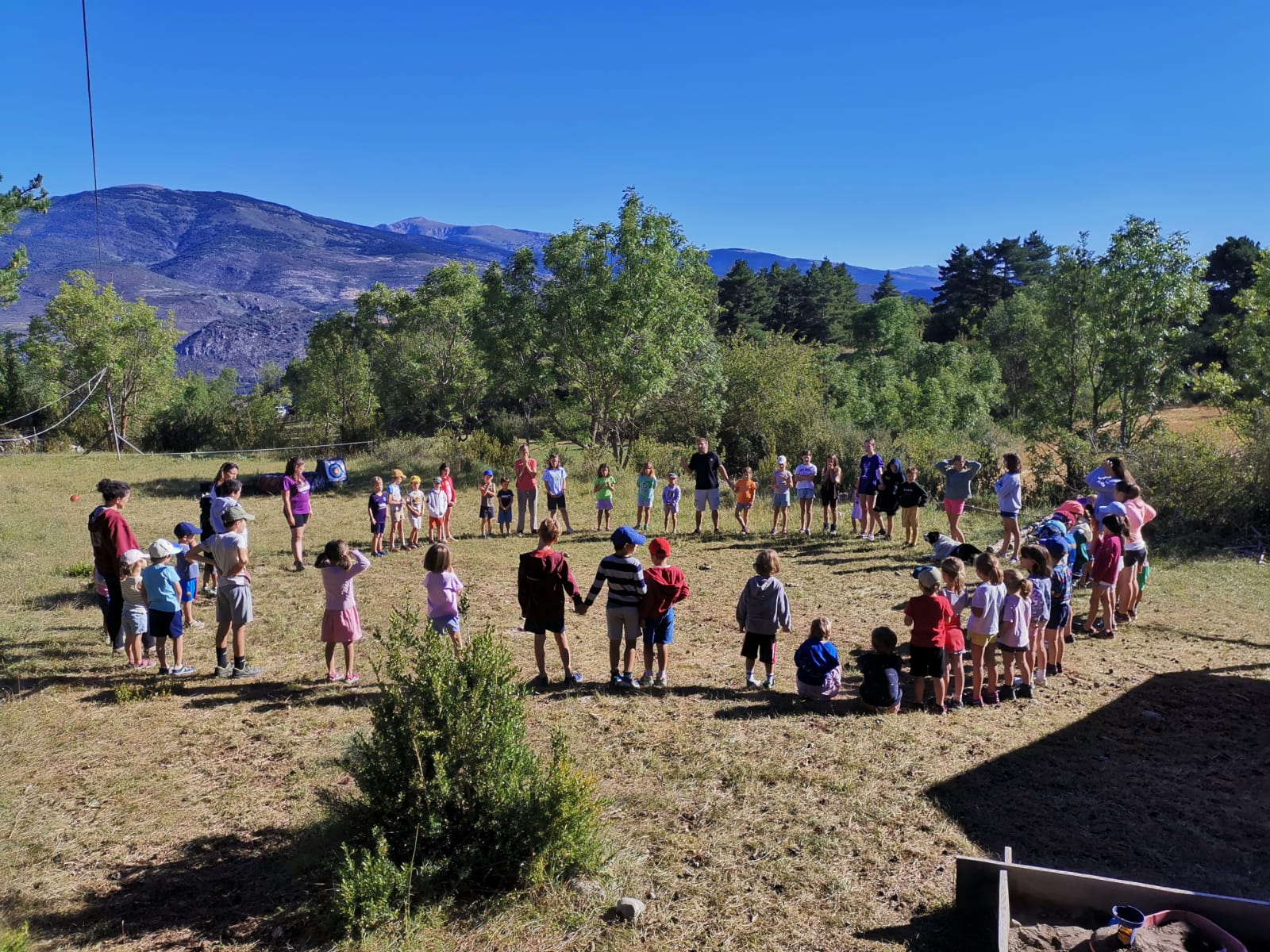 Grup d'infants fent activitats de rotllana al bosc durant el casal